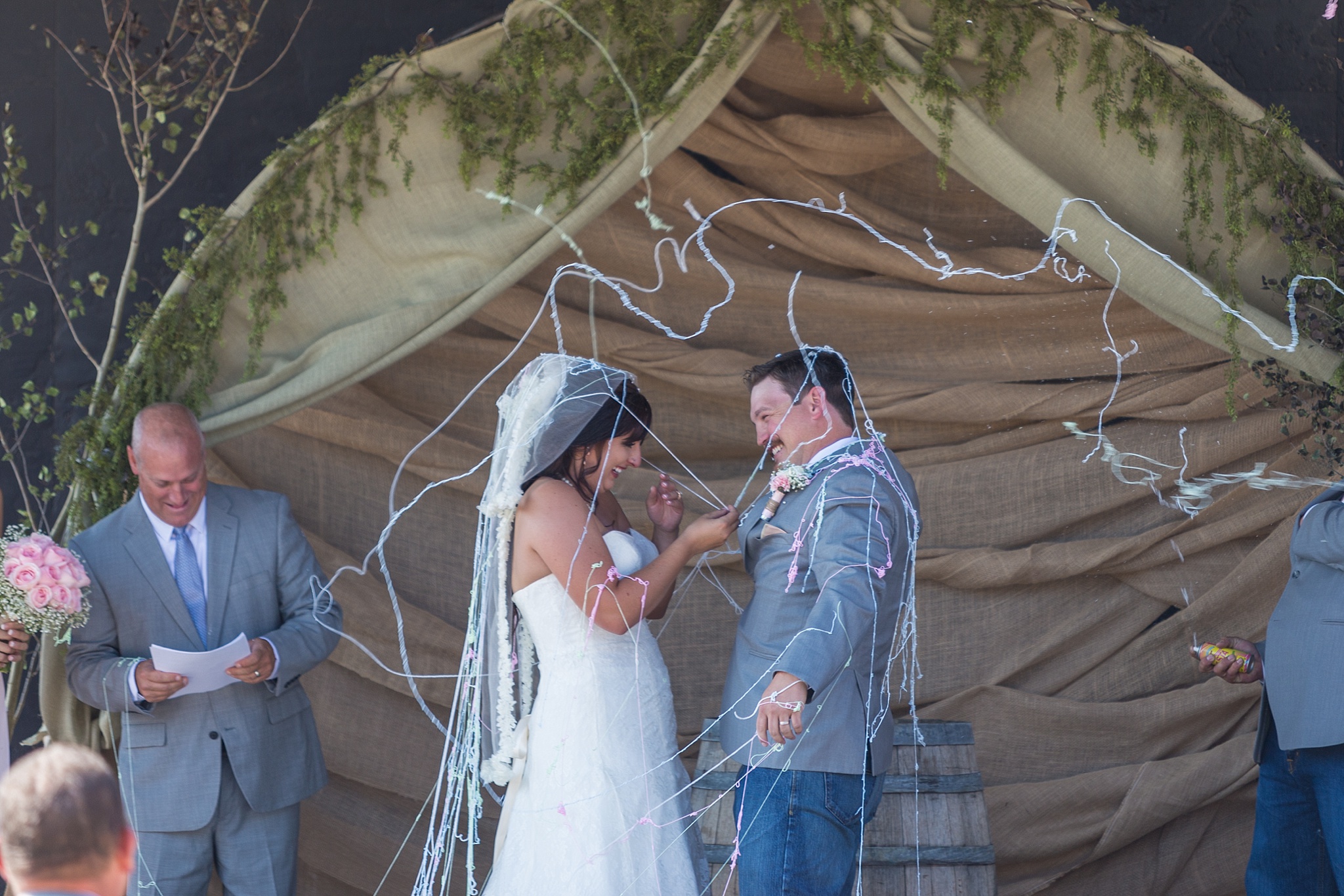 Bride & Groom being sprayed with silly string. Katie & Jake’s Castle Rock Wedding at the Douglas County Fairgrounds by Colorado Wedding Photographer, Jennifer Garza. Colorado Wedding Photographer, Colorado Wedding Photography, Douglas County Fairgrounds Wedding Photography, Castle Rock Wedding Photography, Castle Rock Wedding Photographer, Colorado Wedding Photography, Colorado Wedding Photographer, Colorado Wedding, Rustic Wedding, Colorado Bride, Rocky Mountain Bride